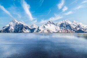 Frozen lake with jagged snowy hills and blue sky with clouds