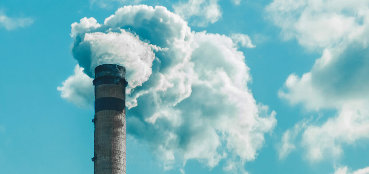 Smokestack releasing white smoke, blue sky with clouds