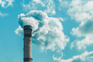 Smokestack releasing white smoke, blue sky with clouds